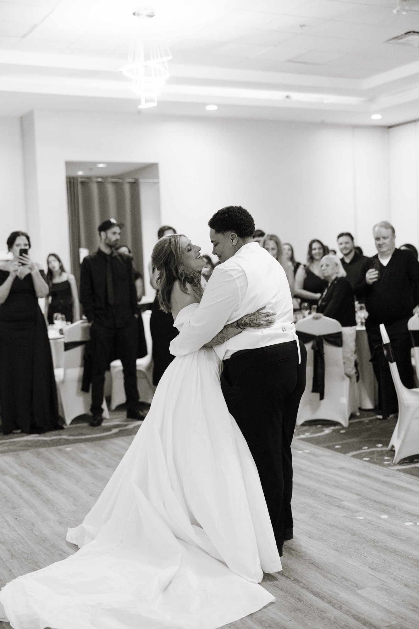 First dance in black and white, guests cheering behind the couple